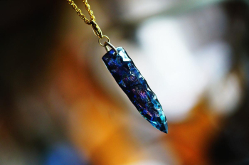 星空を宿すArrowhead 光に照らされた矢じり型ペンダント。柔らかな光とシャープなカットが絶妙に融合し、繊細ながらも力強い印象を与えます。チェーンが引き立てることで、首元での存在感が増しています。 ラフォルム ガラスジュエリー ガラスアクセサリー