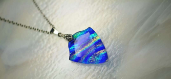 ラフォルム ガラスジュエリー ガラスアクセサリー Blue wave emblem 鮮やかなブルーと青紫色のガラスを、波打つ盾のようなエンブレム型に仕上げました。内部を横切るダイクロガラスの煌きは、光を受けるとグリーンや金色を帯び、海面を走る光の波…