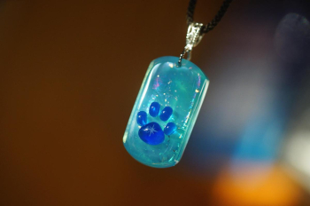 ラフォルム ガラスジュエリー ガラスアクセサリー Stellar Paw Tag 青白磁のようなやさしい青緑のガラスに、宇宙のような煌めきとマーブル模様を閉じ込めたドッグタグ型ペンダント。
中央には紺碧色の肉球。手のひら部分には、八方に広がる星の…