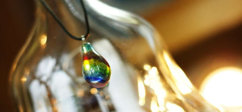 ラフォルム ガラスジュエリー ガラスアクセサリー Colorful shower ふっくらとしたしずくの中へ、虹色の光がシャワーのように降り注ぎます。赤や黄色、緑、ブルーが縦に重なり、内部に施した青いイリデセント（ラメ）が光を受けて瑞々しく煌くペン…