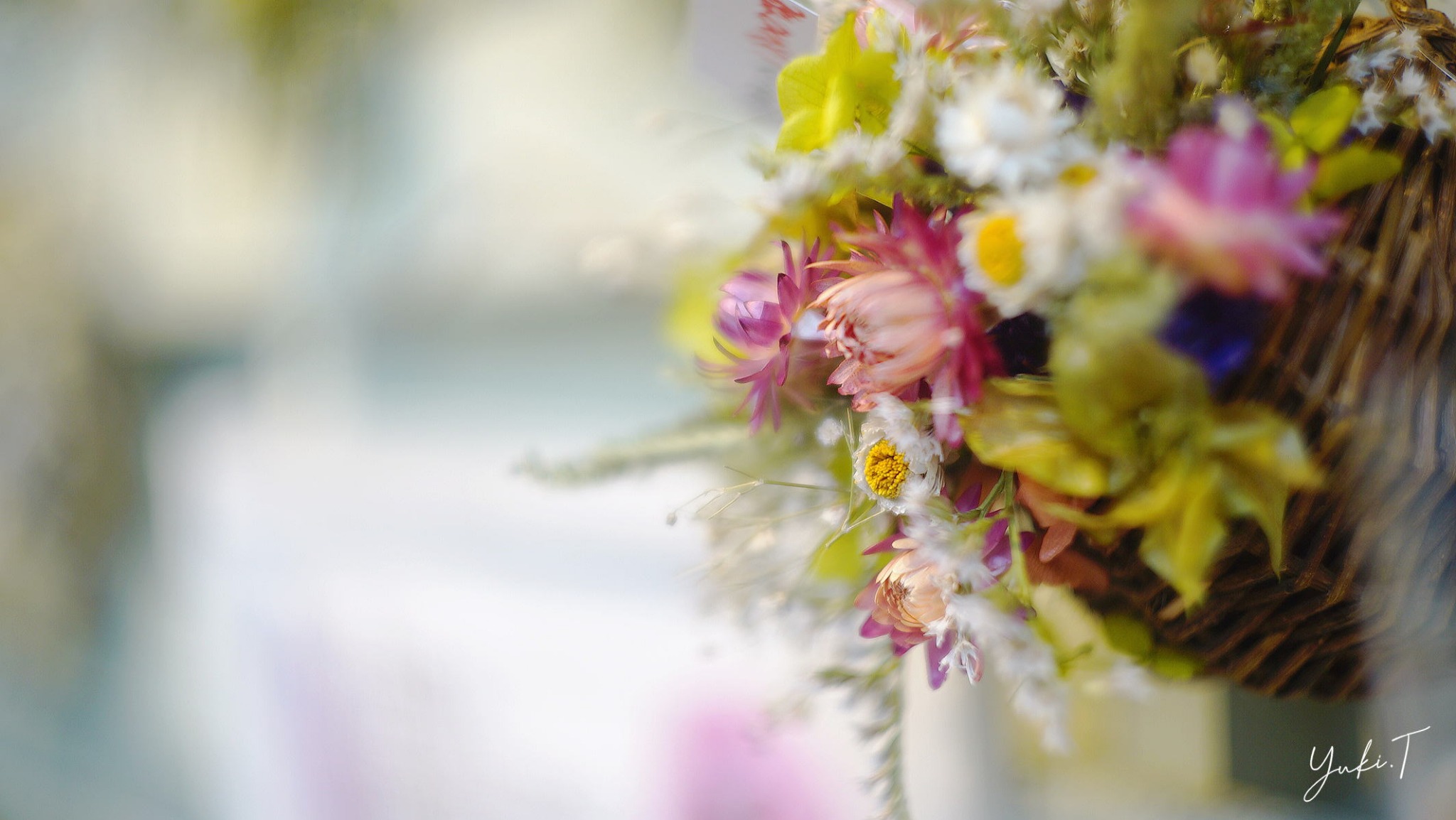窓辺の光を受ける、ピンクや白の花を束ねた花飾り