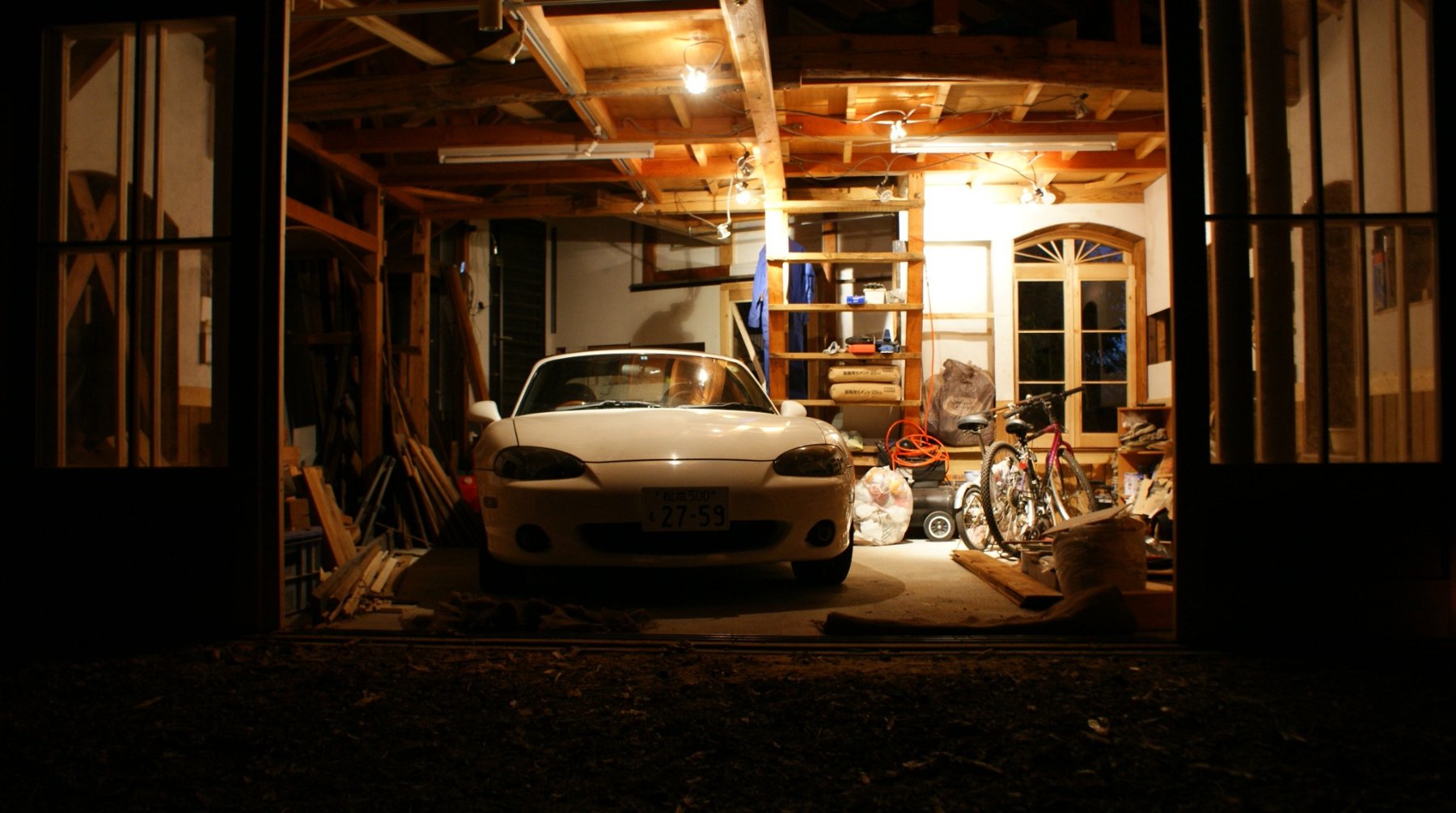 夜のガレージ。車と道具のある、灯りの下。